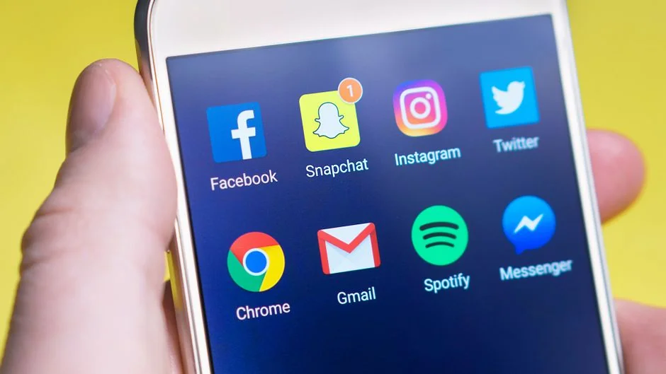 A hand holding a smartphone displaying a photo app with diverse media.